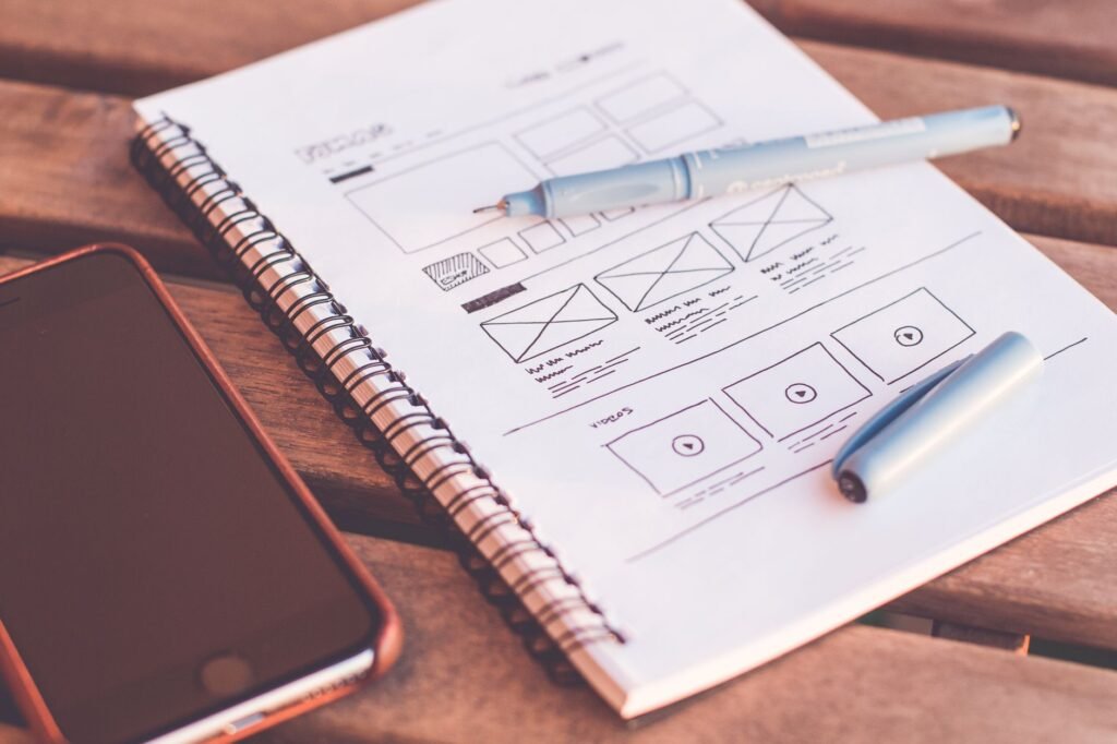 Designer planning a website redesign with wireframes and a laptop